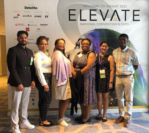A group of six students standing in front of NABA Elevate Convention sign