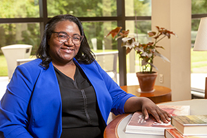 Happy black woman with blue blazer in an office setting, smiling at the camera