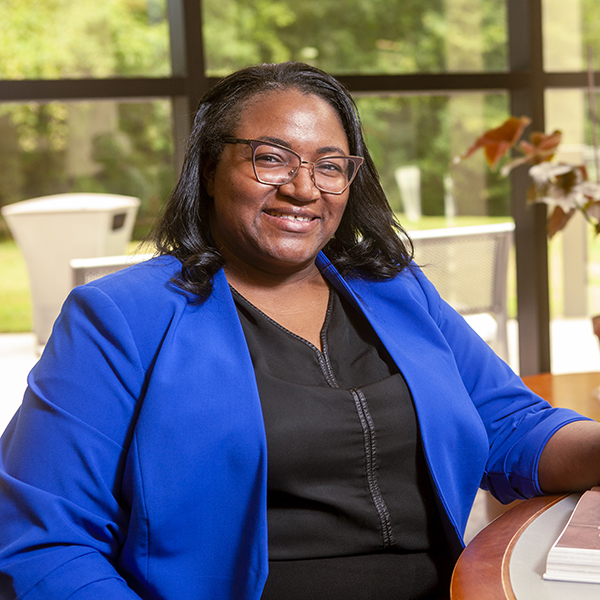 Happy black woman with blue blazer in an office setting, smiling at the camera