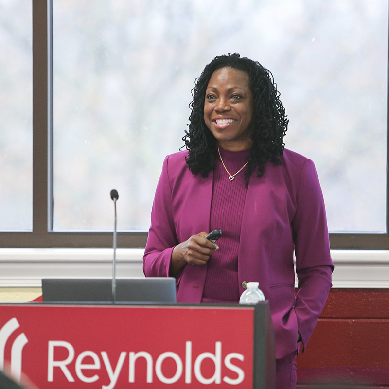Reynolds Community College President Dr. Falicia Williams addressing an audience from behind a branded red podium.