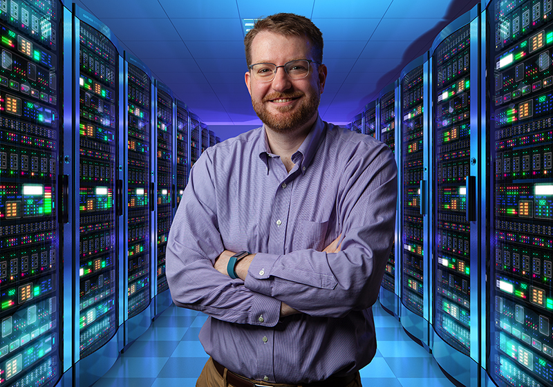 Matt Sakach stands in IT Engineering space with lights in background