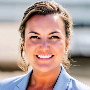 Melissa Brooks, white, blonde woman wearing light blue blouse smiles at the camera