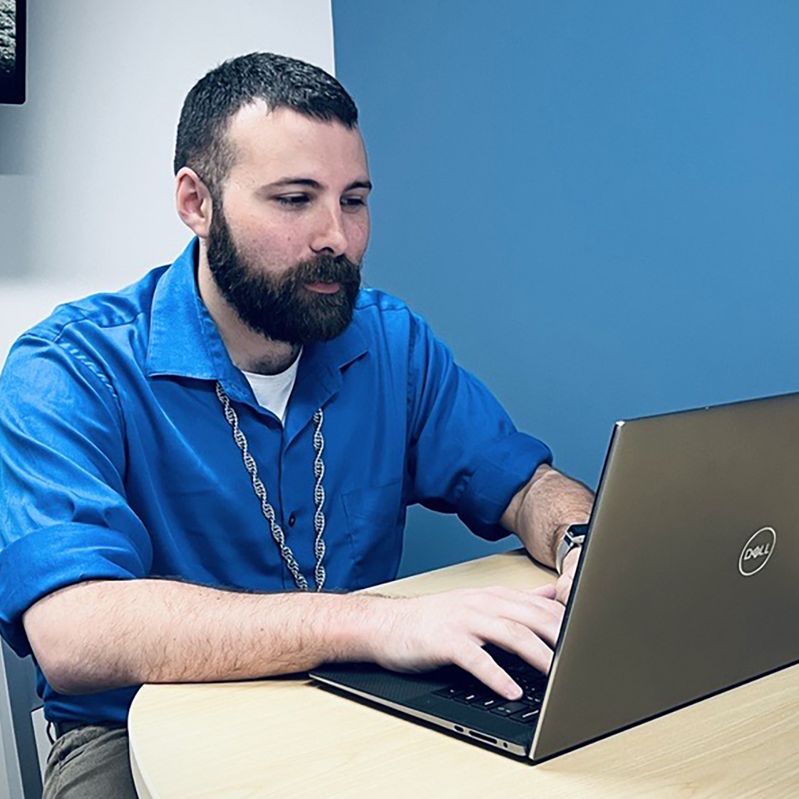 Ryan Campbell, with beard and in blue shirt works on his computer