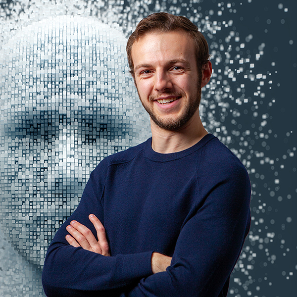 Ryan Lingo stands confidently in blue shirt, arms crossed in front of a blue background with the shape of a human face, meant as a visualization of personal data.