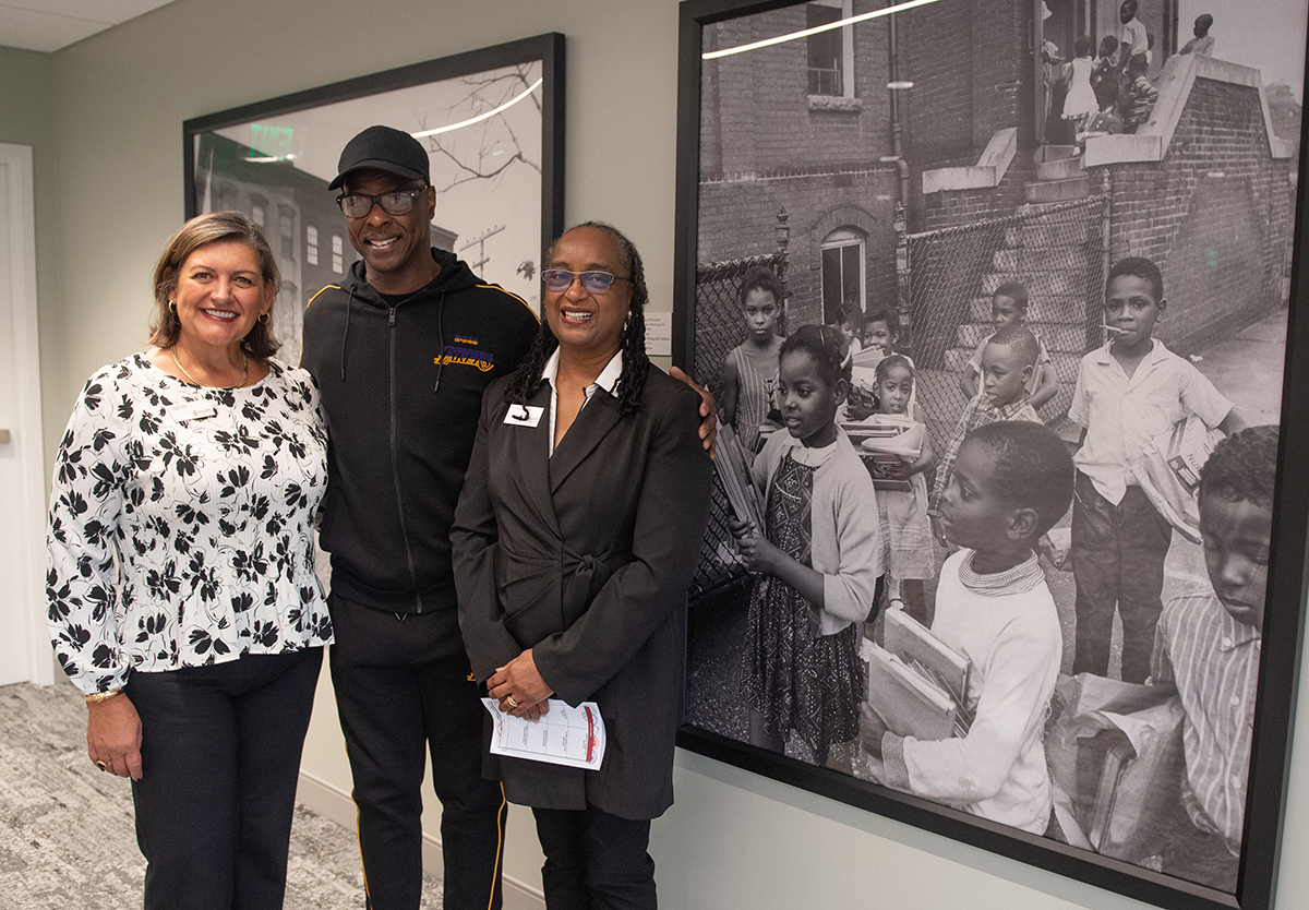 Clayton Jones and Georgette Harris stand in front of a photo from 1965 of children in front of Navy Hill School 