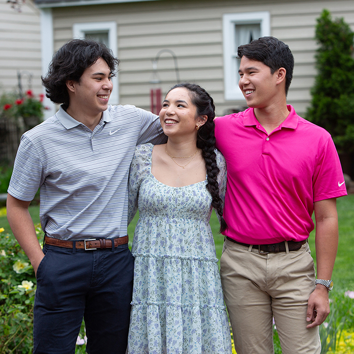 Siblings Noah, Kylie, and Jacob Inocensio looking at each other in support, in a garden setting.