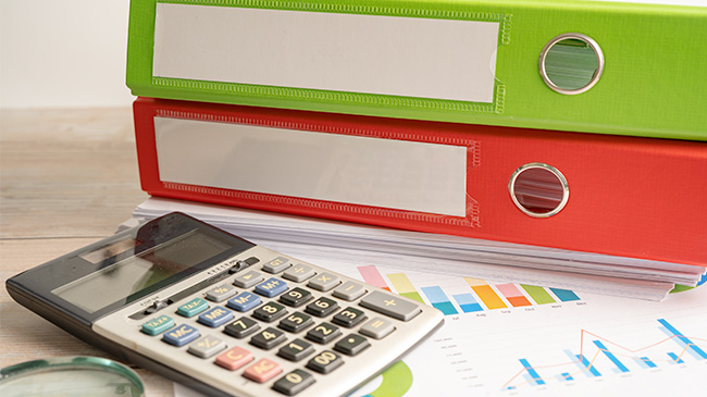 A stack of binders and a calculator neatly arranged on a table.